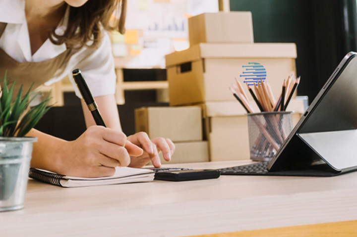 woman writing next to cardboard boxes